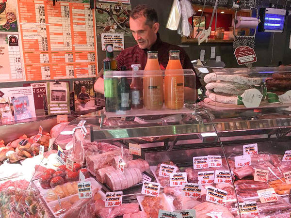 Didier Tass, behind the counter of his butcher shop, says he purchases meat from small farmers who raise cows and butcher them humanely and in small quantities.