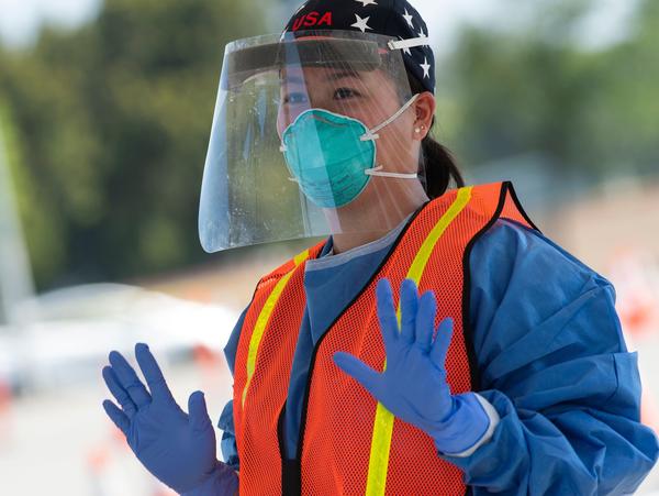A health worker dons protective gear at a drive-through COVID-19 testing site set up by the Los Angeles Fire Department in Inglewood, Calif., on Monday.