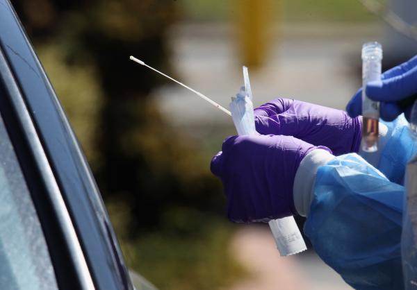 Medical workers prepare to use a swab to administer a coronavirus test at a drive-through center on March 21 in Jericho, N.Y.