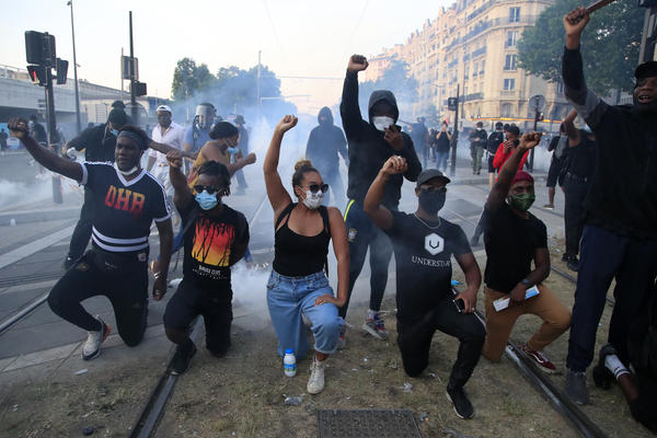Protesters on Tuesday in Paris take a knee, as riot officers fire tear gas and scattered protesters throw projectiles and set fires at an unauthorized demonstration against police violence and racial injustice. Several thousand people rallied peacefully for two hours around the main Paris courthouse in tribute to George Floyd and to Adama Traoré, a French black man who died in police custody.