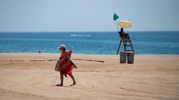 A woman passes a lifeguard this week on the beach in Lloret de Mar, Spain. The European Union is considering which countries should be allowed to send tourists to its member nations as travel restrictions begin to ease in the pandemic.