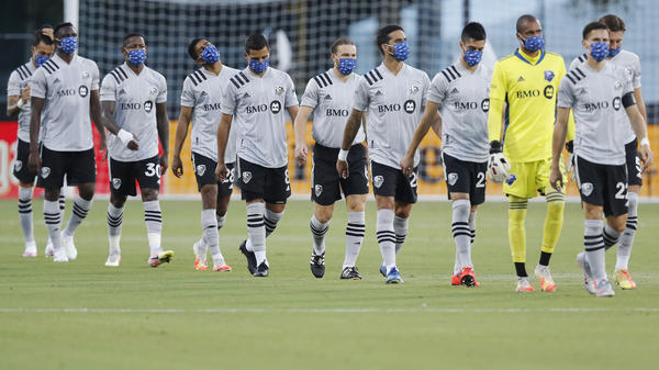 Members of the Montreal Impact, wearing masks, take the field for their match against Toronto FC as part of the MLS Is Back Tournament Thursday in Reunion, Fla.