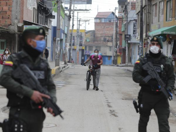 Police stand guard during a government order for residents to stay home, to help contain the spread of the new coronavirus, as a resident walks to a food store in Soacha on the outskirts of Bogotá, Colombia, on March 25.