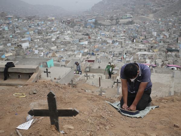 A relative prays at the Mártires 19 de Julio Cemetery on the outskirts of Lima, Peru, on Aug. 20. Peru has one of the world's highest per capita coronavirus-related death tolls, according to Johns Hopkins University.