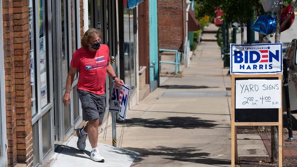 A man walks out of the Washington County Democratic Party office last week, in the suburbs of Pittsburgh, after taking a Joe Biden yard sign. Because of the coronavirus pandemic, Biden's campaign isn't doing any in-person door-knocking.