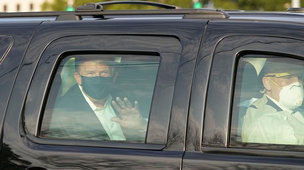 President Trump waves from a motorcade outside Walter Reed Medical Center, accompanied by Secret Service agents on Sunday.