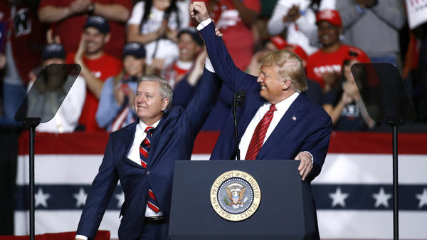 Sen. Lindsey Graham, R-S.C., stands onstage with President Trump during a Feb. 28 campaign rally in North Charleston, S.C. His allegiance to Trump has left some moderate voters feeling snubbed and switching allegiances to Democrat Jaime Harrison.