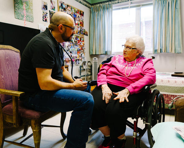 Glenn Hurst gives Jeannette Massen a checkup at the Northcrest Living Center in Council Bluffs, Iowa. As they prepare to caucus, voters weigh which candidate to support and what health care should look like in the future.