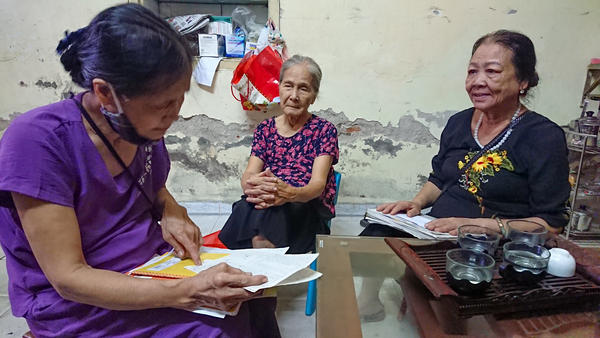 Dao Thi Hoa, right, chairwoman of the Intergenerational Self Help Club in the Khuong Din ward of Hanoi in Vietnam, checks the club's account book with other members.