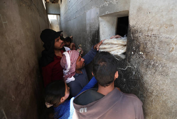 Syrians buy bread at a shop in the town of Binnish in the country's northwestern Idlib province in June. Nowadays, people say they're waiting up to six hours in line for a meager government bread ration.