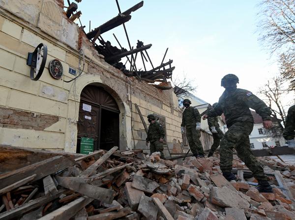 Croatian soldiers walk next to damaged buildings Tuesday in Petrinja, some 30 miles from the capital, Zagreb, after the town was hit by a 6.4 magnitude earthquake.