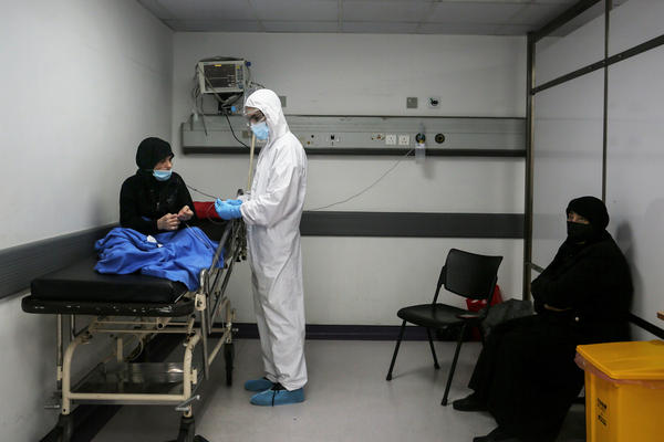 Inside an emergency room at Rafik Hariri Hospital on Nov. 17, a medic wearing full protective gear checks a woman who might have the coronavirus. Beirut hospitals are reaching maximum capacity amid an influx of coronavirus patients.