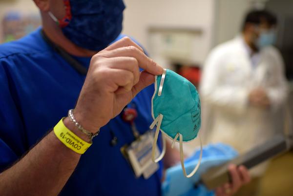 A health worker holds an N95 respirator in the emergency room at OakBend Medical Center in Richmond, Texas, in July. N95s are tested and approved by a federal agency as having demonstrated that they can filter out a minimum of 95% of airborne particles.