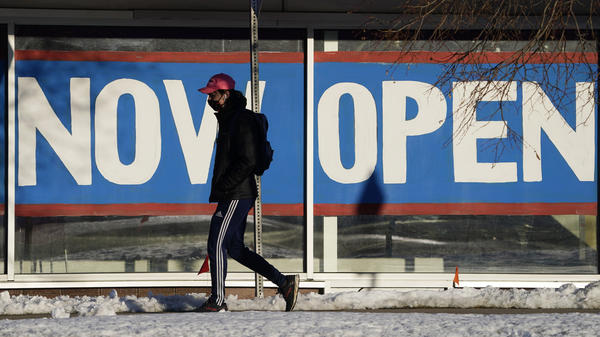 A pedestrian on Feb. 25 walks past the window of a restaurant with a sign promoting its re-opening in Boulder, Colo. Congress on Wednesday passed a $1.9 trillion stimulus plan, which is expected to provide a strong boost to economic growth.