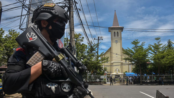 A police officer stands guard outside the Sacred Heart of Jesus Cathedral in Makassar, Indonesia, on Sunday. Two suicide bombers attacked the Roman Catholic compound, injuring at least 20 people.