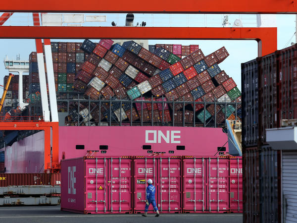 A worker walks past the ONE Apus container ship and its dislodged containers at the Kobe Port in Japan in December. The vessel suffered a massive stack collapse and lost 1,816 containers at sea during severe weather on Nov. 30.
