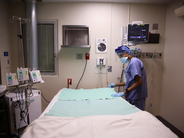 Intensive Care Unit nurse Subramanya Kirugulige prepares a bed for an arriving COVID-19 patient at Roseland Community Hospital in Chicago in December. A large study has found that people with severe initial cases of COVID-19 tend to be at greater risk of more health problems later on.