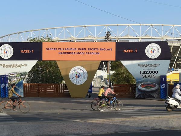 Cyclists cycle past the main entrance of the Narendra Modi Stadium in Ahmedabad, India, a venue where cricket matches were taking place during the 2021 Indian Premier League — until it was suspended.