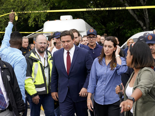 Florida Gov. Ron DeSantis (center) and Lt. Gov. Jeanette Nuñez (center right) arrive for a news conference near where a section of a 12-story beachfront condo building collapsed on Thursday in the town of Surfside.