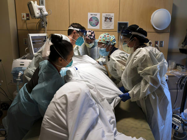 Hospital workers move a patient into the prone (face down) position, which can help increase the lung capacity of some COVID-19 patients. The medical team was photographed Nov. 19 at Providence Holy Cross Medical Center in Los Angeles.