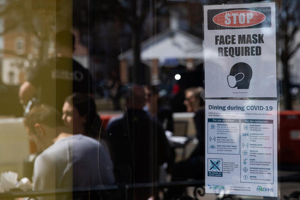 A sign requiring face masks and COVID-19 protocols is displayed at a restaurant in Plymouth, Mich., on March 21. Coronavirus cases in Michigan are skyrocketing after months of steep declines, one sign that a new surge may be starting.
