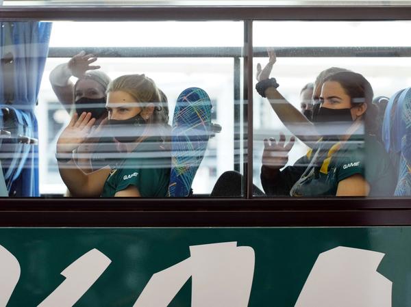 Australian softball players, the first foreign team to arrive for the Tokyo Olympic Games, wave from their bus after arriving at Narita International Airport on June 1.