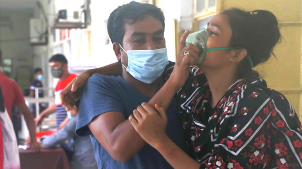 A man assists a patient with difficulty breathing at the Medical College Hospital in Rajshahi, Bangladesh, on June 16, as the delta variant of the coronavirus quickly spread.