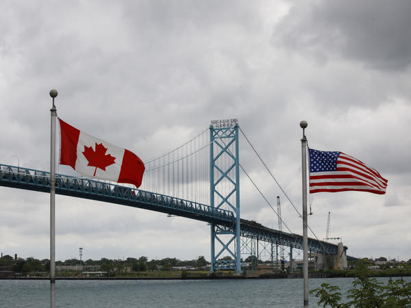 Canadian and American flags fly near the Ambassador Bridge connecting Canada to the U.S. in Windsor, Ontario, in May. Half of respondents in a poll of Canadians this month by Nanos Research said restrictions on travel across the U.S.-Canada border should not be eliminated until this fall or next year.