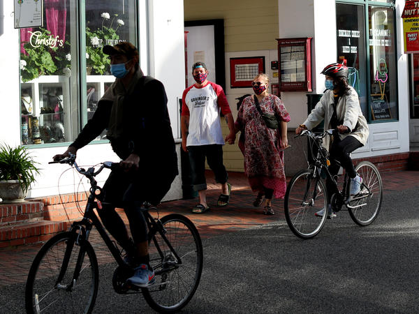Pedestrians and cyclists head down Commercial Street in Provincetown, Mass., in May 2020. A study of a new outbreak in Provincetown found that three-quarters of those infected with the virus were fully vaccinated.