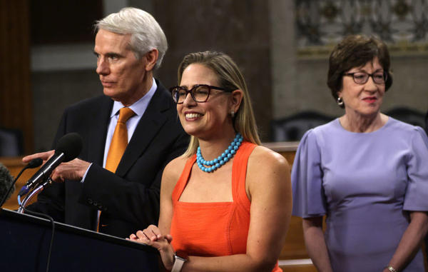 Sens. Rob Portman of Ohio and Kyrsten Sinema of Arizona field reporters' questions last week as Sen. Susan Collins looks on during a news conference about the bipartisan infrastructure deal.