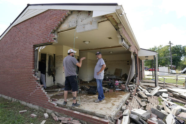 Brian Mitchell (right) looks through the damaged home of his mother-in-law along with family friend Chris Hoover on Sunday in Waverly, Tenn. Heavy rains caused flooding Saturday in Middle Tennessee and have resulted in multiple deaths as homes and rural roads were washed away.