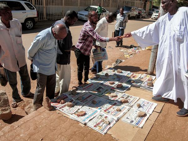 People in Sudan's capital, Khartoum, browse newspapers with headlines featuring the 2020 U.S. general election results. After 27 years, the State Department has removed Sudan from a list of state sponsors of terrorism.