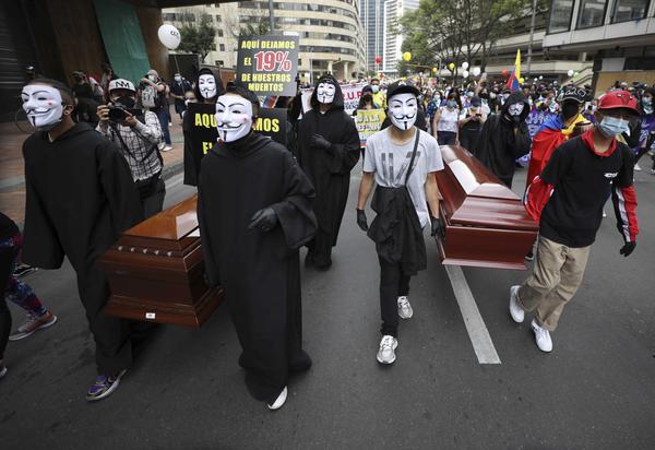Protesters wearing Guy Fawkes masks carry empty coffins during a national strike to protest a government proposal that would raise taxes, in Bogotá, Colombia, on Wednesday.