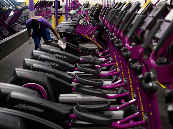A Planet Fitness employee cleans equipment before a gym's reopening in March in Inglewood, Calif., after being closed due to COVID-19. Reduced access to recreation likely has contributed to weight gain during the pandemic.