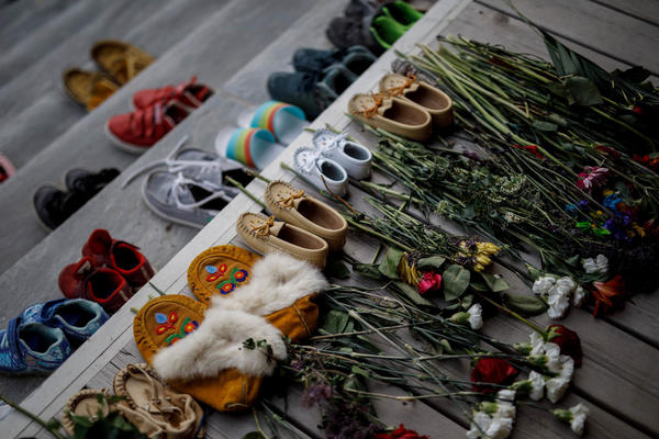 Flowers, shoes and moccasins sit on the steps of the main entrance of the former Mohawk Institute, which was a residential school for Indigenous kids, in Brantford, Ontario. The memorial is to honor the children whose remains were discovered in unmarked graves in recent months in Canada.