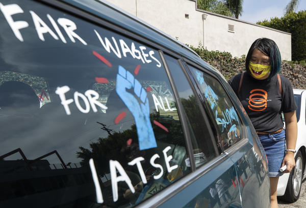 Crystal Kan, a storyboard artist, draws signs on cars of IATSE union members during a rally in Los Angeles in September.