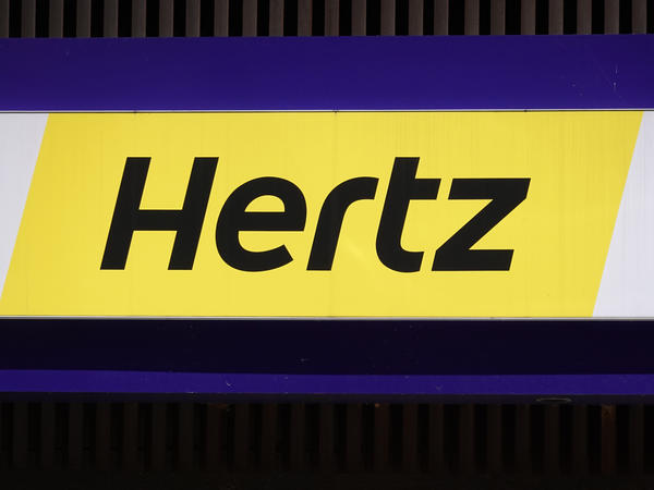 A sign hangs above a Hertz rental car office on Aug. 4, 2020, in Chicago. The company said it's buying 100,000 Teslas in a bold move to diversify into electric vehicles.