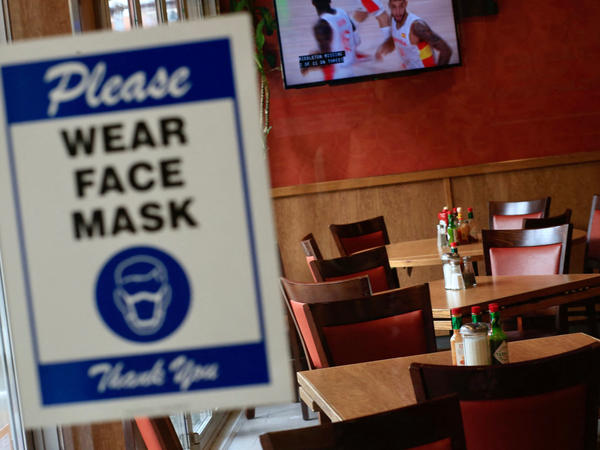 A sign asking patrons to wear a mask is seen at the entrance of a restaurant in New York City on Aug. 3. The spread of the delta variant led to sharply slower economic growth in the July-to-September quarter.