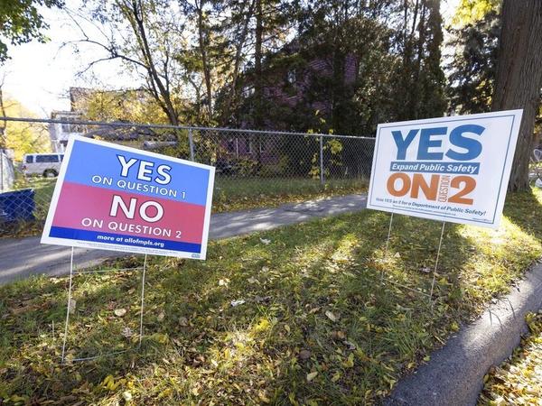 Competing lawn signs are placed outside a polling place Tuesday in Minneapolis. Voters decided not to replace the city's police department with a new Department of Public Safety. The election comes more than a year after George Floyd's death launched a movement to defund or abolish police across the country.