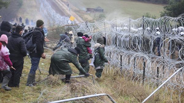 Migrants from the Middle East and elsewhere break down the fence as they gather at the Belarus-Poland border near Grodno, Belarus on Monday.