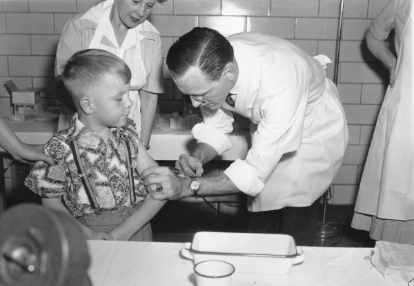 Dr. Richard Mulvaney of Mclean, Va., injects the new polio vaccine into the arm of 6-year-old Randall Kerr, the first of some 100 children to be inoculated on April 26, 1954.