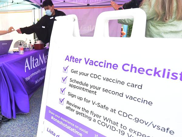 A nurse from AltaMed Health Services hands out the vaccine card to people after receiving their Covid-19 vaccine in Los Angeles, California on August 17, 2021.