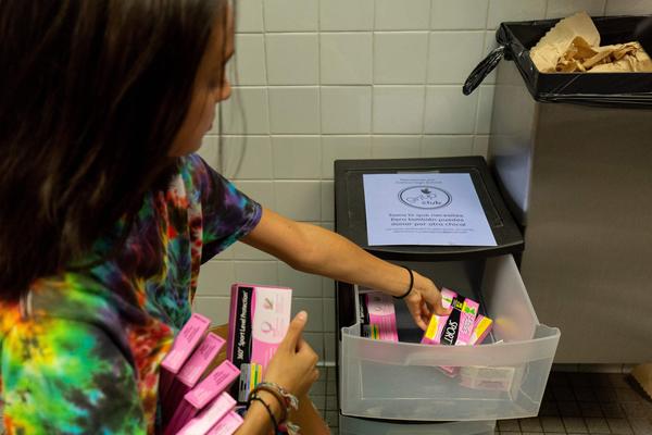 A student stocks a school bathroom with free pads and tampons to push for menstrual equity, at Justice High School in Falls Church, Va., in 2019.