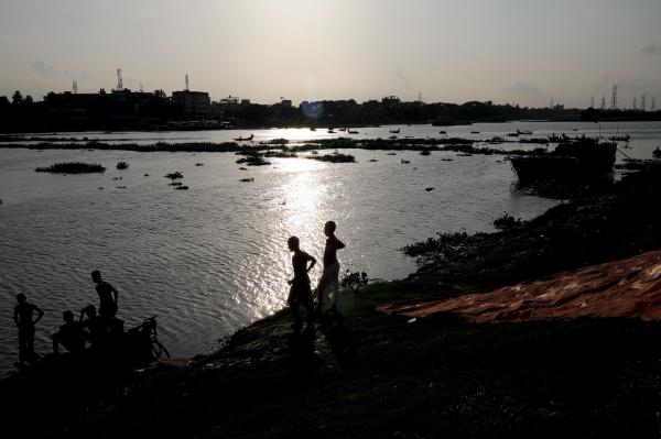 Two boys stand at the edge of the Buriganga River in Dhaka, Bangladesh, in July. A recent study finds that globally, boys and young men made up two-thirds of all deaths among young people in 2019.
