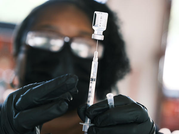 A person prepares to administer a Pfizer COVID vaccine at a clinic in Ferguson, Missouri in August 2021. Merriam-Webster has chosen "vaccine" as the word of the year, citing a sustained surge in lookups.