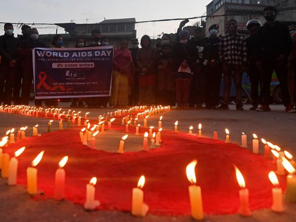 Volunteers stand after lighting candles in the shape of a red ribbon during an awareness event ahead of World AIDS Day in Kathmandu on Tuesday.