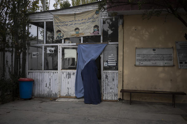 A woman enters the hospital in Mir Bacha Kot, Afghanistan, on Oct. 26, 2021. Health care workers continue to work without salaries, without medicine and with frequent power cuts as Afghanistan's economy crumbles. (Bram Janssen/AP)
