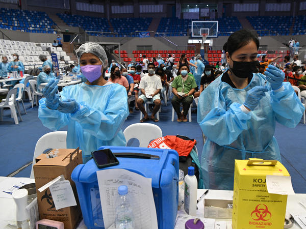 Health workers prepare COVID-19 vaccines at a coliseum in suburban Manila on November 29 — part of a massive 3-day vaccination drive launched by the government. It was one of 8,000 vaccination centers set up during the drive.