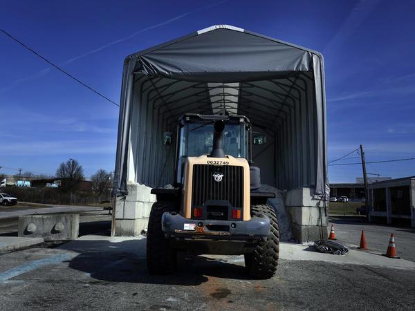 A tractor sits in front of a pile of salt used to create brine that will help clear road of ice and snow ahead of a winter storm in Forest Park, Ga., on Friday.