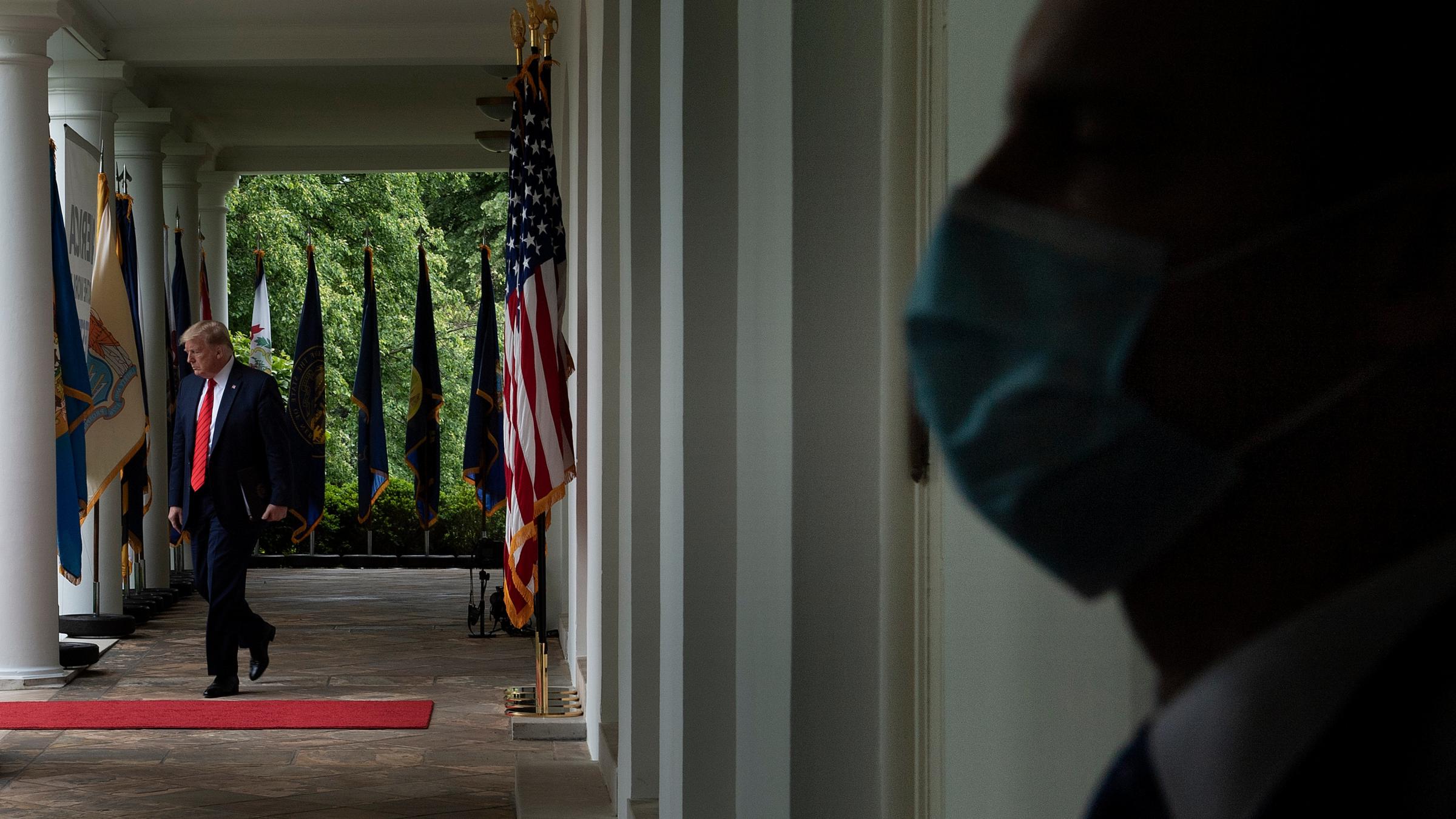 A member of the Secret Service wears a surgical mask as President Trump arrives for a news conference Monday